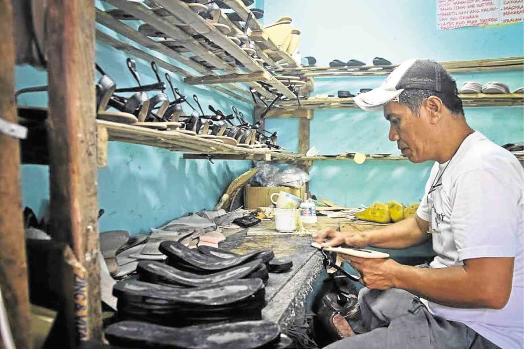 Shoemaker Jonie Vitor, 52, applies glue to a sandal sole at a home shoemaking workshop in Liliw, Laguna.