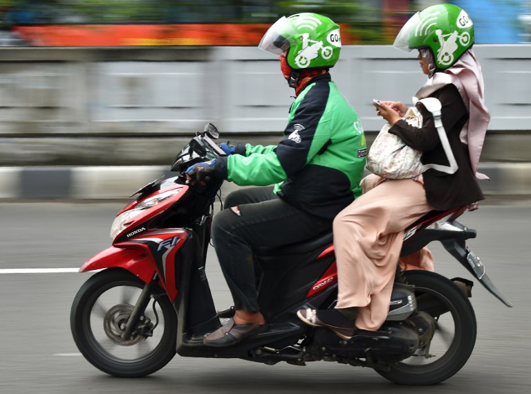 A Gojek rider transports a passenger in Jakarta on February 2, 2017. / AFP PHOTO / Bay ISMOYO