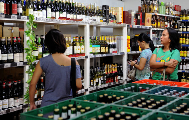 Shoppers at a supermarket looking at display of alcoholic beverages