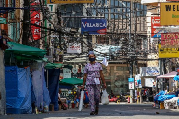 A resident walks along an almost empty street in Manila on March 29, 2021, on day one of government's imposing stricker lockdown, as hospitals in the capital struggle to cope with a surge in coronavirus infections