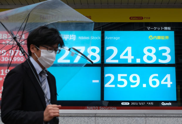 A man walks past an electronic quotation board displaying the closing numbers of share price at the Tokyo Stock Exchange in Tokyo on May 17, 2021. (Photo by Kazuhiro NOGI / AFP)