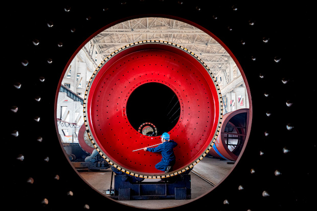 An employee measures a newly manufactured ball mill machine at a factory in Nantong, Jiangsu