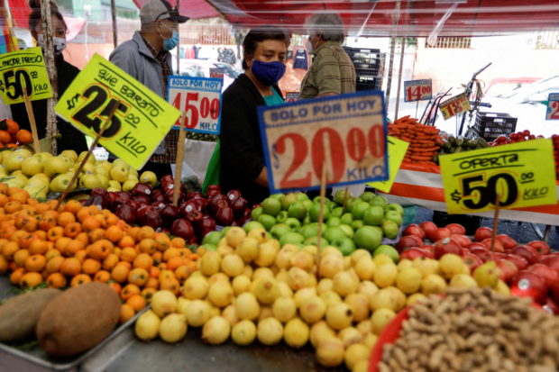 People walk past fruit stall at a street market in Mexico City