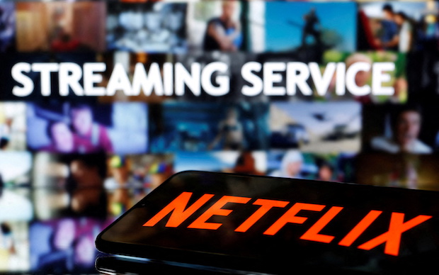 A smartphone with the Netflix logo lies in front of the displayed words "Streaming service"