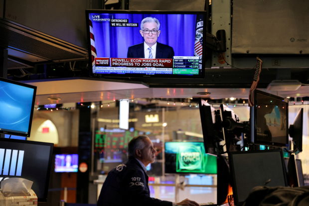 FILE PHOTO: Federal Reserve Chair Jerome Powell is seen delivering remarks on a screen as a trader works on the trading floor at the New York Stock Exchange (NYSE) in Manhattan, New York City, U.S., December 15, 2021. REUTERS/Andrew Kelly