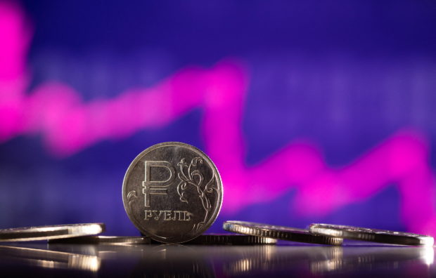 Russian Rouble coins are seen in front of displayed descending stock graph in this illustration taken, February 24, 2022. REUTERS/Dado Ruvic/Illustration
