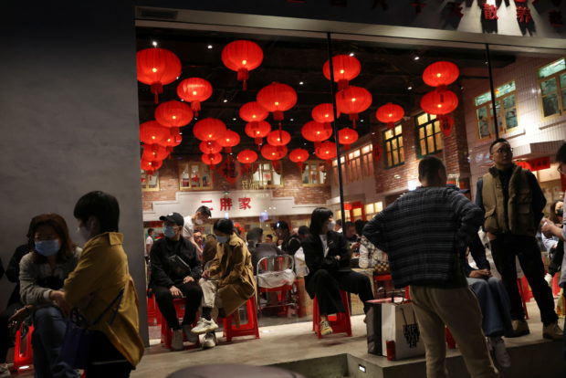 Customers wait in front of a restaurant in Beijing, China April 15, 2022. REUTERS/Tingshu Wang/Files