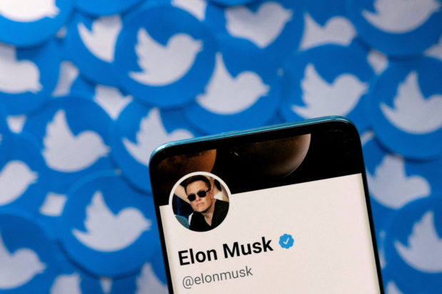 Elon Musk photo on a phone with Twitter logo in background