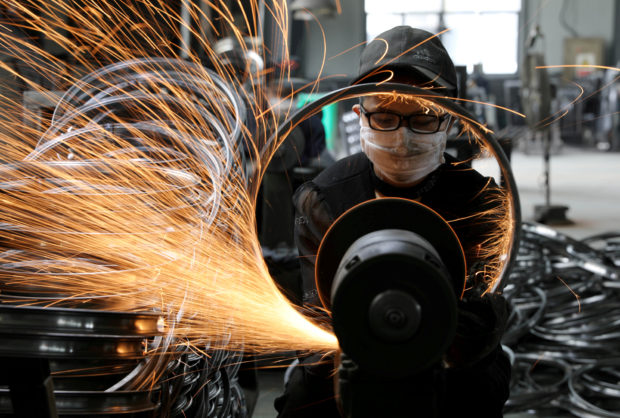 Worker welds bicycle steel rim in a factory