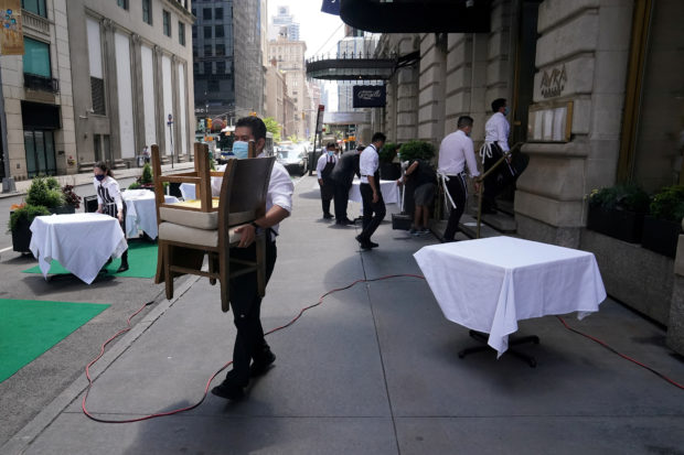 A waiter setting up table in front of a restaurant