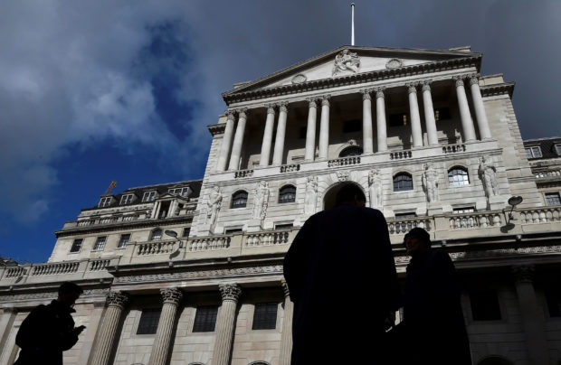 Men walk past the Bank of England