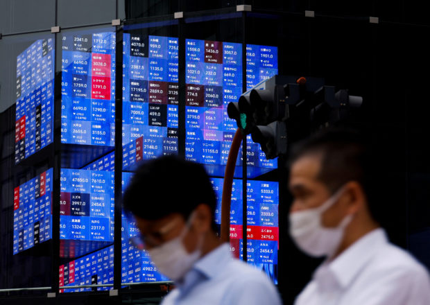 People passing by an electronic screen showing Japan's Nikkei share price index