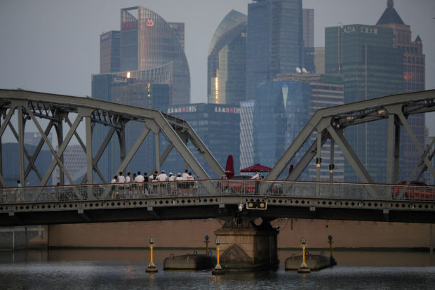 People stand on a bridge near the Bund in Shanghai