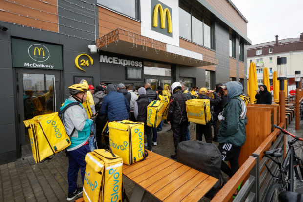 Food couriers wait to pick up orders outside a McDonald's restaurant
