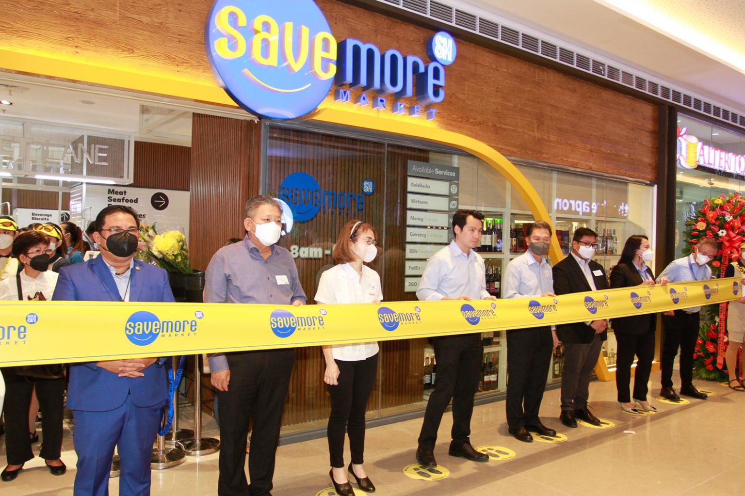 People standing behind a yellow line in front of Save More