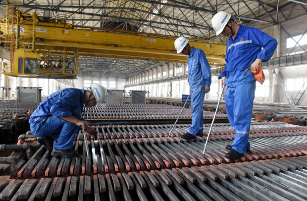 Workers inspecting copper cathodes at Jinlong Copper Plant in China