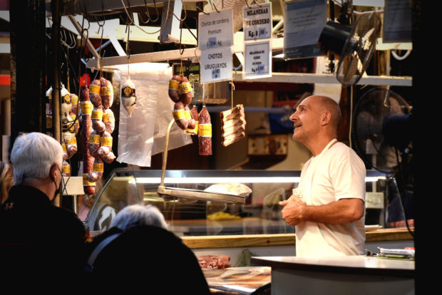 A butcher attends to a customer