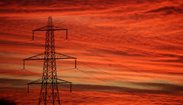 Sun rises behind electricity pylon