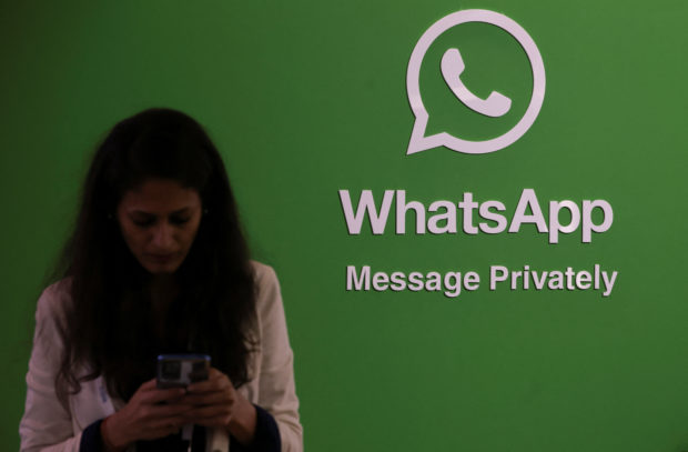 A woman uses her phone with WhatsApp logo in background