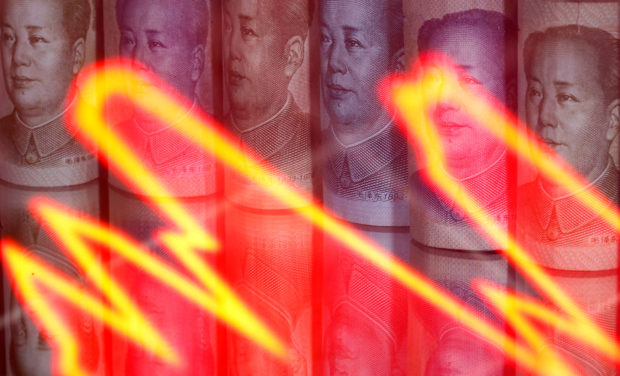 Chinese Yuan notes behind illuminated stock graph