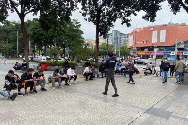 People sit by Shenzhen's main factory recruitment hub