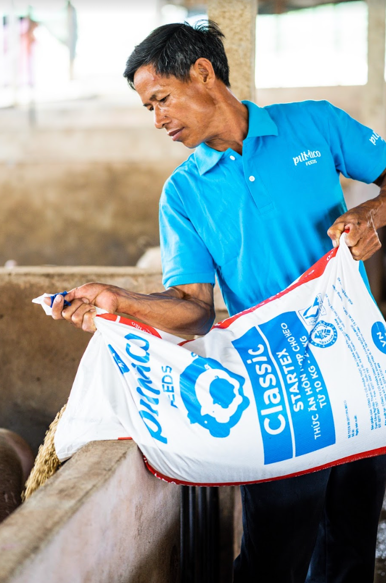 Pilmico employee holds a sack of animal feeds