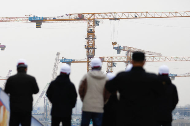 Workers looking at cranes in a construction site in Beijing