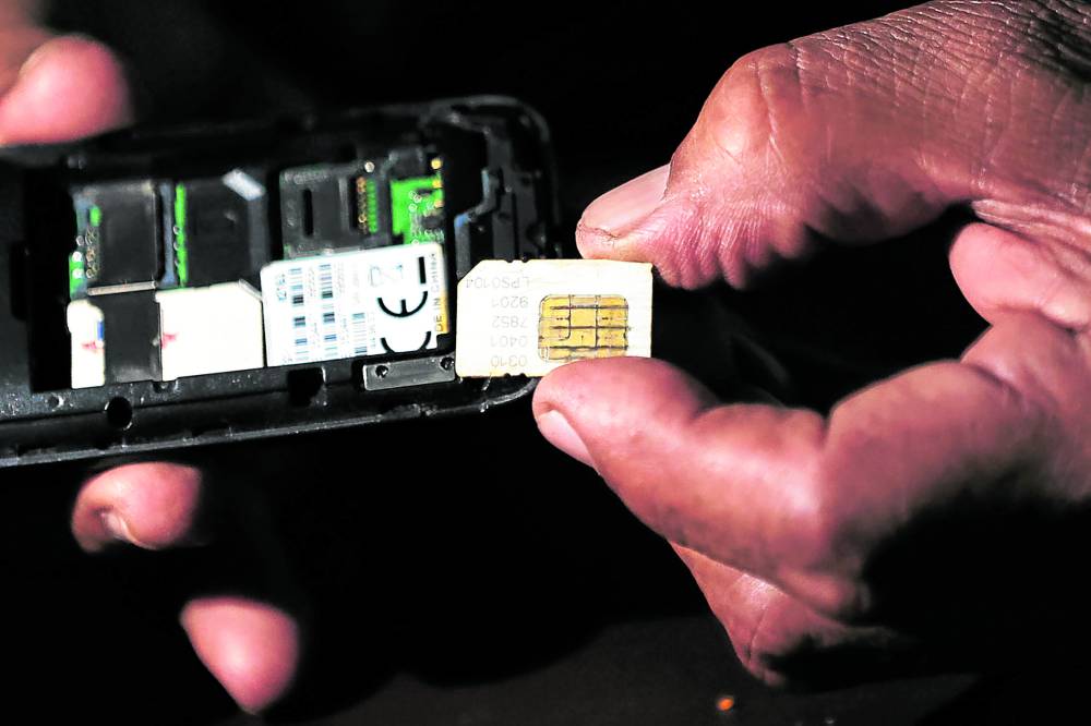 A mobile phone subscriber inspects his subscriber identity module (SIM) card before inserting it into his device. 