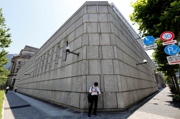 Man looks at his phone in front of the Bank of Japan building in Tokyo