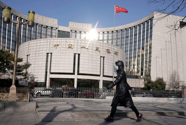 Woman walks past the HQ of People's Bank of China