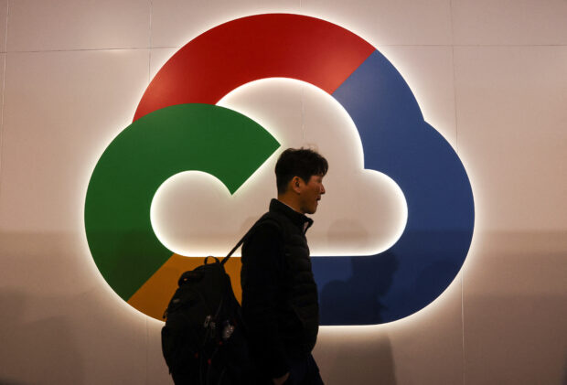 A person walks in front of a Goggle Cloud logo