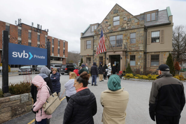 Customers wait in line outside a branch of Silicon Valley Bank in Wellesley, MA