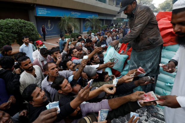 Men reach out to buy subsidized flour in Karachi