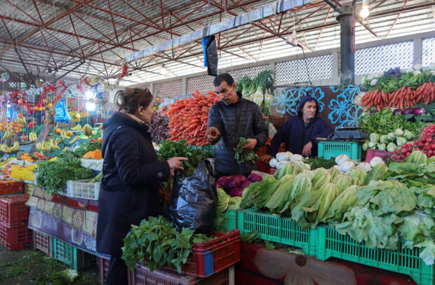 Woman buying from a fruit and vegetable stall in a market in Tunis, Tunisia