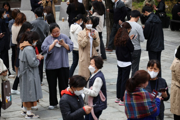 South Korean office workers checking their mobile phones