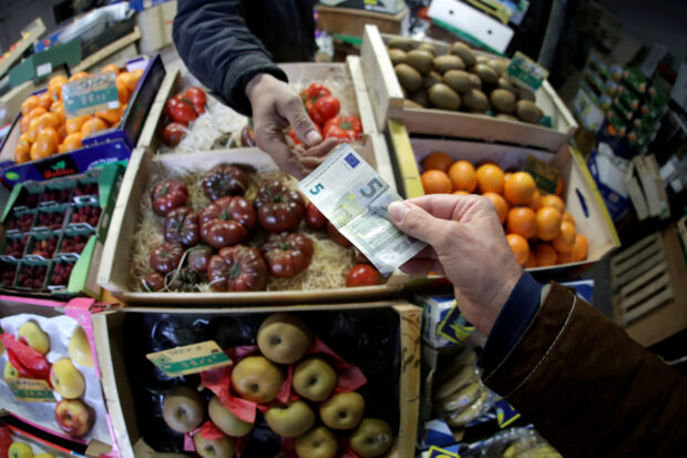 Shopper pays euro bank note in a market in Nice