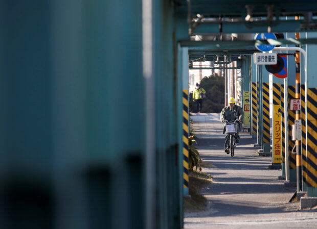 A worker cycles near a factory in Japan