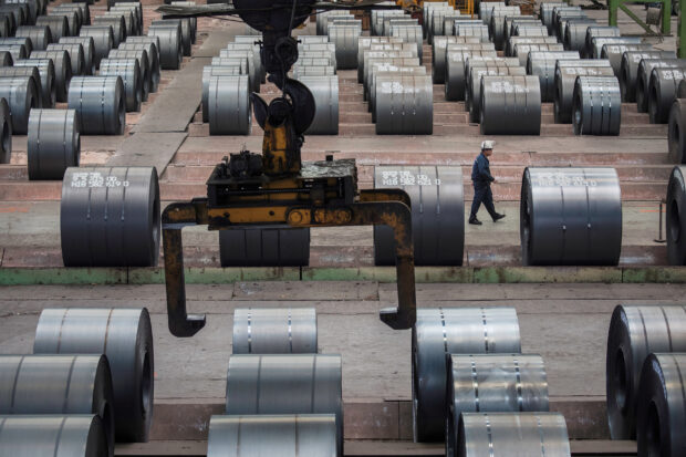 A worker walks past steel rolls at Chongqing Iron and Steel plant in China