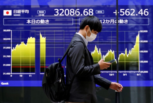 A man walks past an electric monitor showing Japan's Nikkei share average