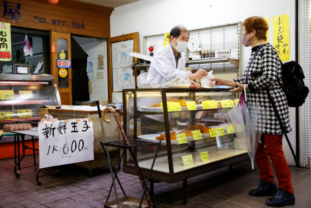 A customer buys cooked food in a market in Tokyo