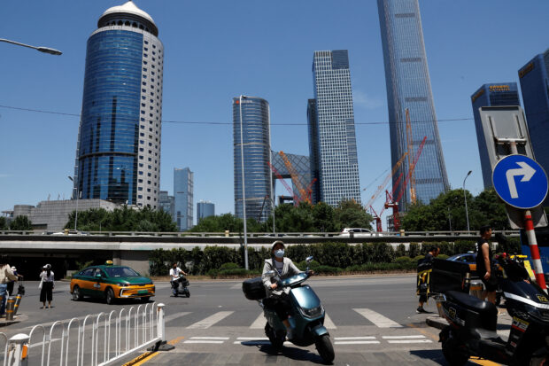 People ride scooters on a street in Beijing's central business district