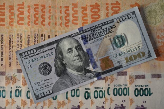Argenina peso bills under a $100 banknote