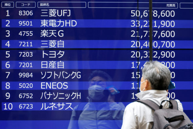 A man looks at an electric monitor displaying a stock quotation outside a bank in Tokyo