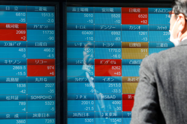 Man checks stock quotes on an electronic stock quotation board in Tokyo