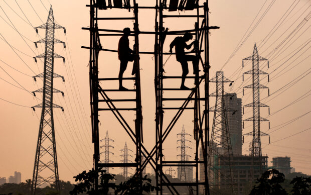Laborers work next to electricity pylons in Mumbai
