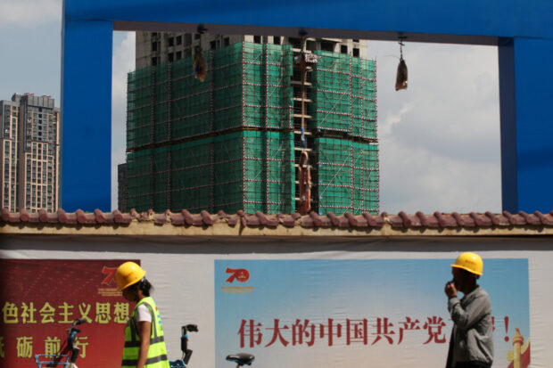 Workers walk past a construction site of residential buildings in Yunnan