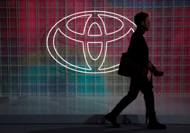 A man walks past a Toyota logo