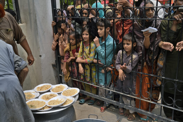 Women and children wait for free food at a distribution point in Lahore, Pakistan