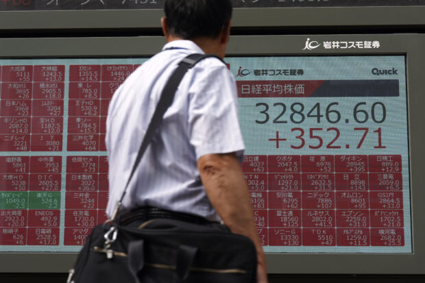 A man checks out an electronic stock board showing Japan's Nikkei index