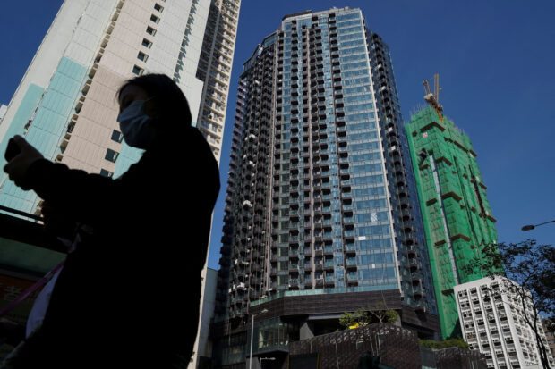 A woman walks by a residential development in Hong Kong